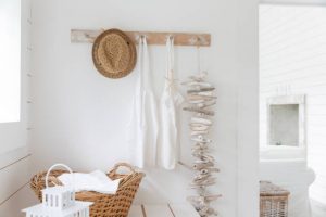 Patère de salle de bain en bois avec panier en osier, linge blanc et guirlande de bois flotté