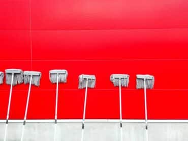 Des balais à frange sur un mur rouge